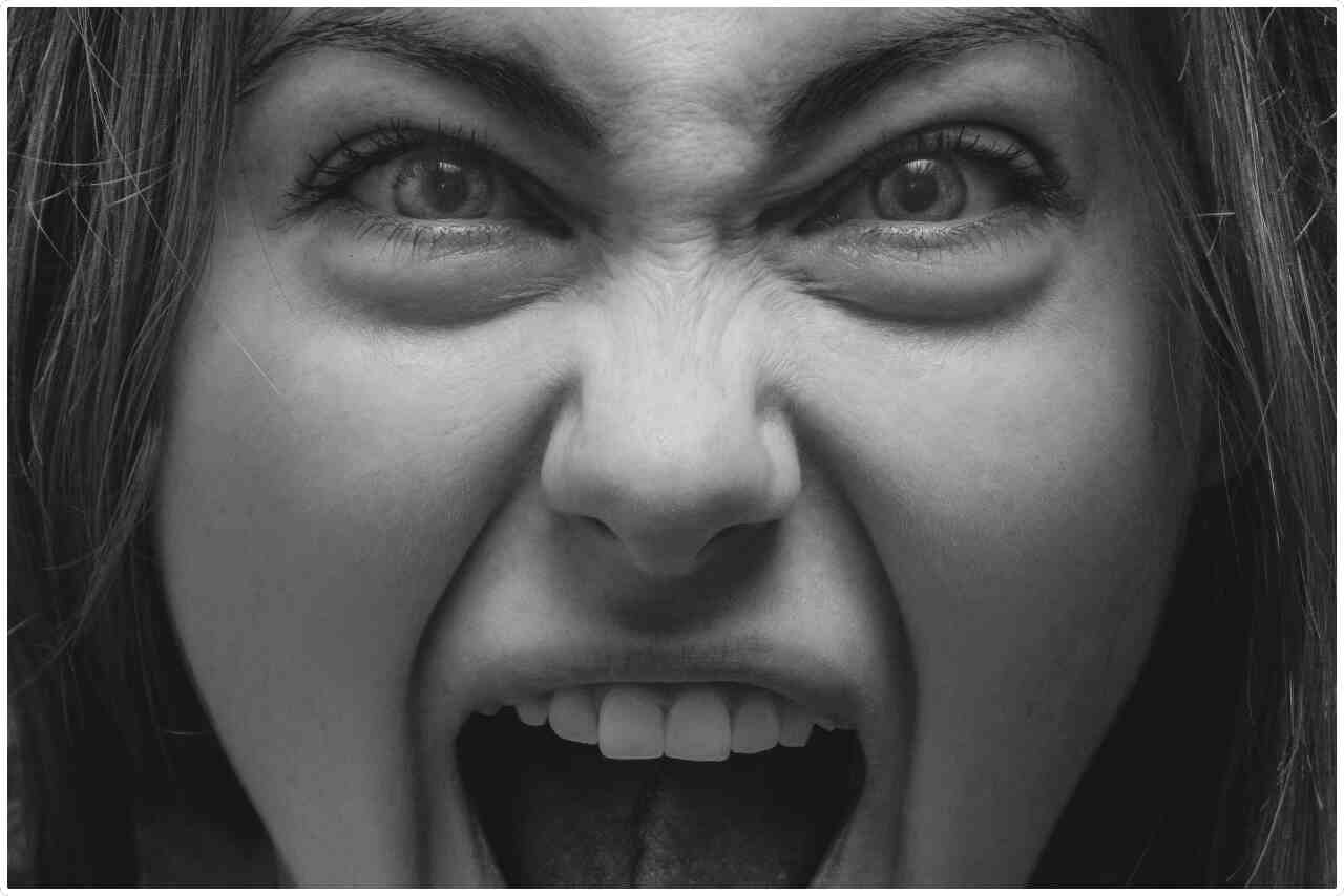 Angry woman with wide-open mouth screaming in frustration